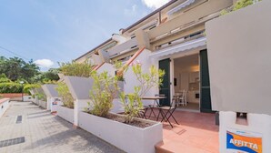 Edificio residencial con patio, mobiliario exterior y un letrero que indica que la propiedad está en alquiler.