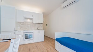 Una cocina compacta con gabinetes blancos, horno integrado y una pequeña mesa de comedor.