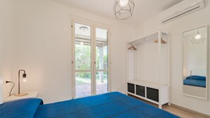 Un dormitorio con una cama grande, un armario, un espejo y una puerta que da a un balcón.