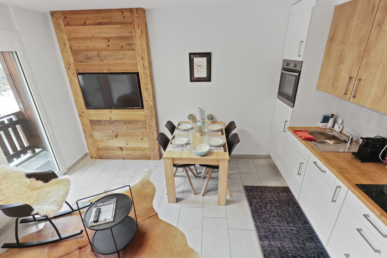 Een compacte keuken met een eethoek, houten details en een inbouwoven.