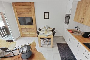 Una cocina compacta con comedor, detalles de madera y horno empotrado.