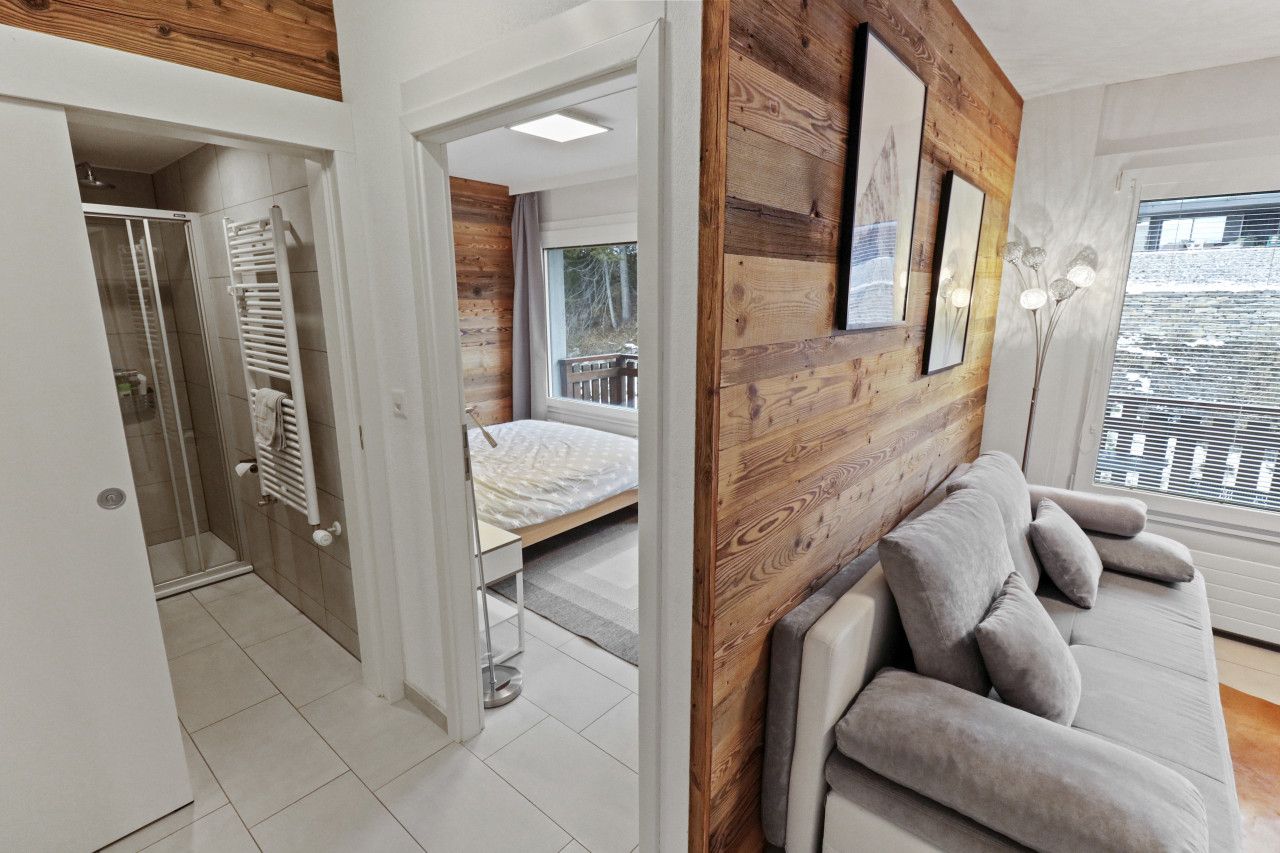 Ein modernes Schlafzimmer mit einer Wand aus Holzpaneelen, einem weißen Sofa und einem Bett.