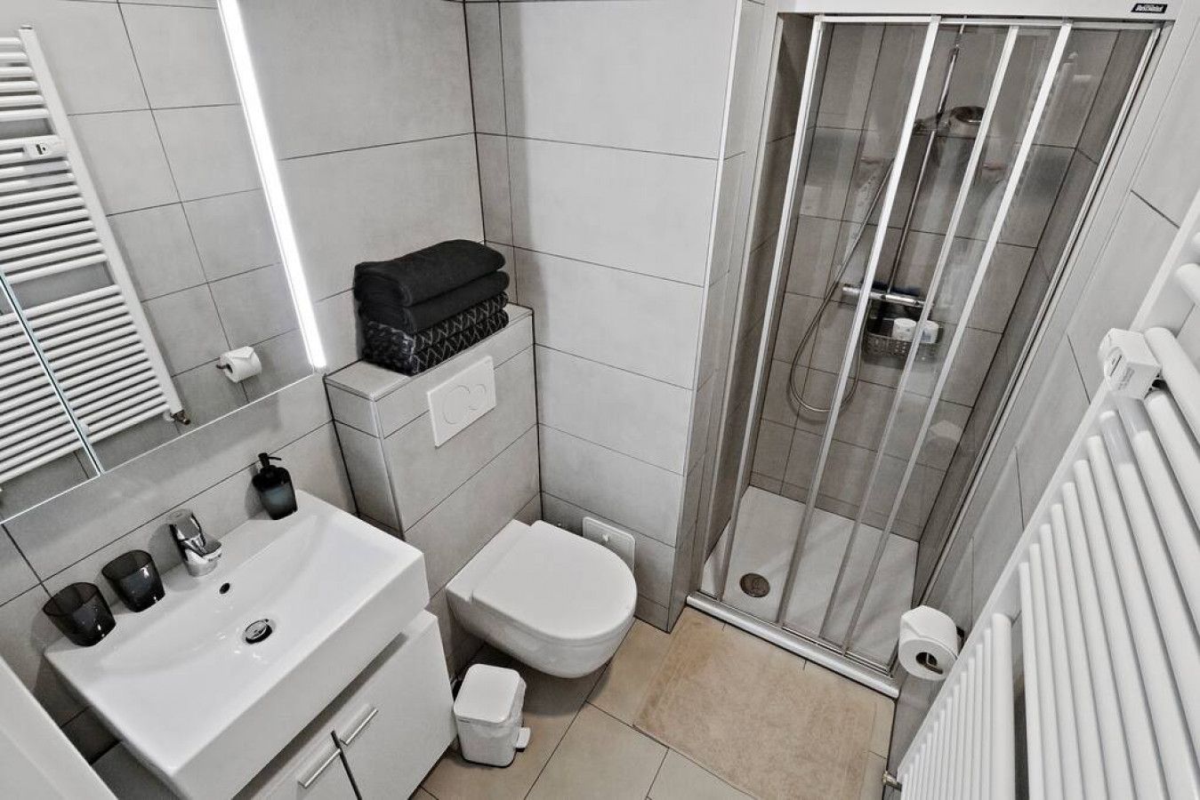 Une salle de bain moderne avec un lavabo, des toilettes et une douche à l’italienne, le tout de couleur blanche.