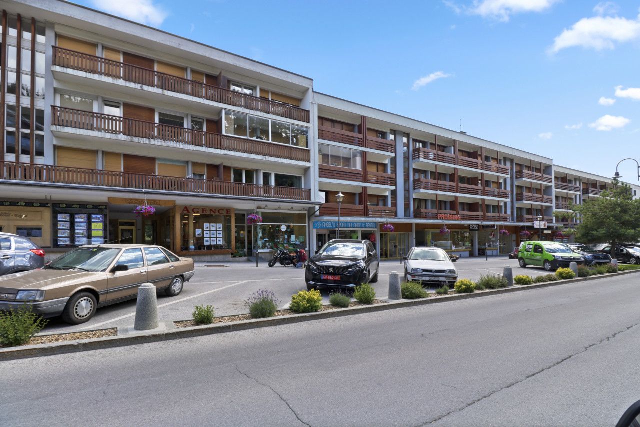 Un hotel de varios pisos con balcones, un estacionamiento y diversas tiendas en la planta baja.
