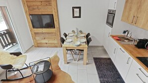 Una cocina compacta con comedor, detalles de madera y horno empotrado.