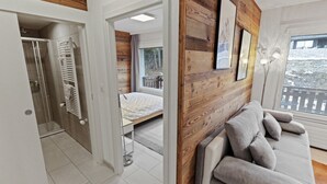 Un dormitorio moderno con una pared de acento de madera, un sofá blanco y una cama.