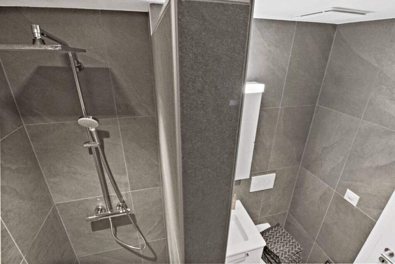 A modern bathroom with a shower, toilet, and sink.