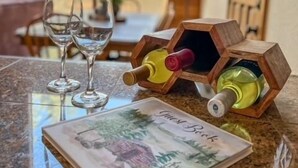Ein Weinschränk aus Holz mit Flaschen auf einer Granit Arbeitsplatte, ein gerahmtes Bild und leere Weingläser.