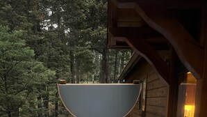 Ein Whirlpool auf einer Holzterrasse mit Blick auf einen Wald.