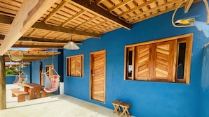 Een kamer met een blauwe wand, houten deuren en een plafond met zichtbare balken. Er staan twee houten banken en een klein tafeltje.