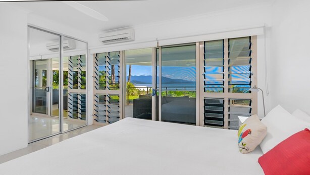 Una camera da letto con un letto grande, vista sul mare e un balcone con porta in vetro.