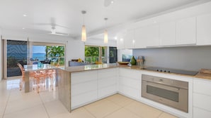 Una cucina moderna con mobili bianchi, un'isola centrale e vista sull'esterno.