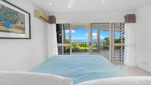 Una camera da letto con un letto, un quadro, un condizionatore e un balcone con vista sul mare.