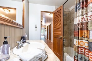 Een bad/douchecombinatie, een haardroger, handdoeken, toiletpapier