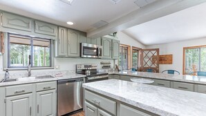 Uma cozinha moderna com armários verde-claros, eletrodomésticos de aço inoxidável e uma grande ilha.