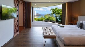 Una habitación de hotel moderna con una cama grande, un televisor y un balcón con vista al mar.