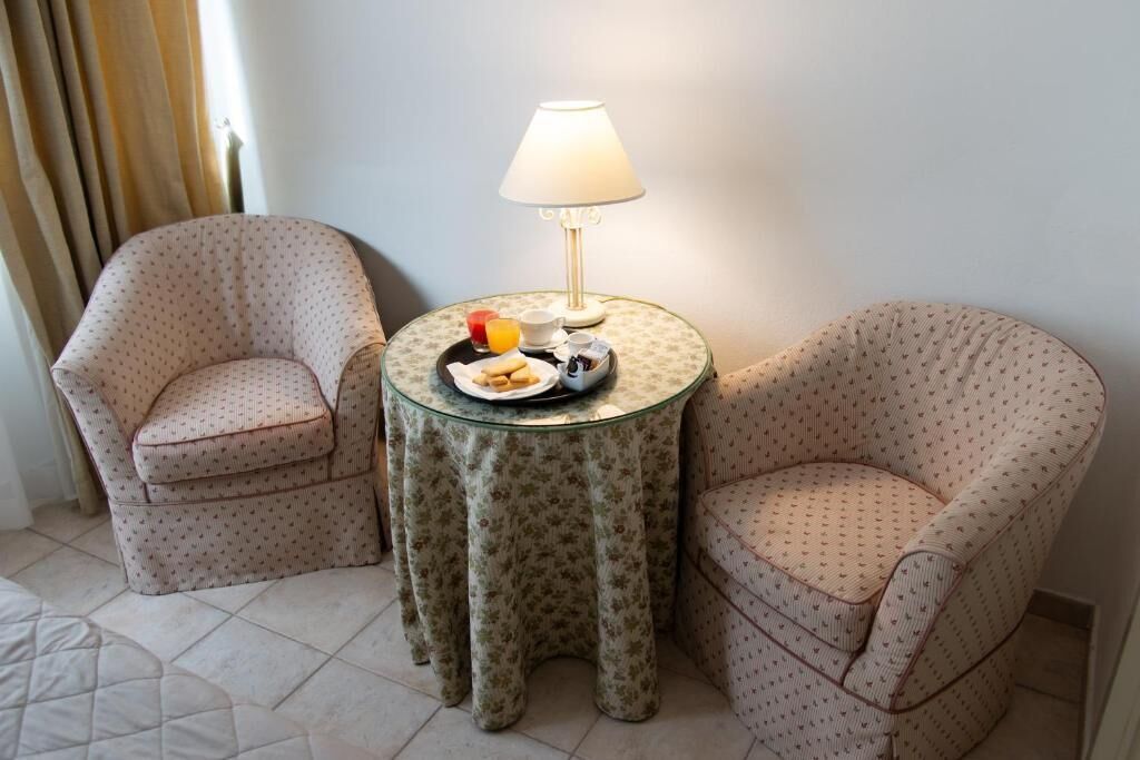 Une pièce comprenant deux fauteuils à motifs, une petite table ronde avec une lampe et un plateau contenant des articles pour le petit-déjeuner.