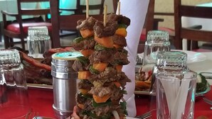 A plate with skewered meat, potatoes, and a salad.