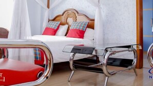 A bedroom with a canopy bed, a bedside table, and a red chair.