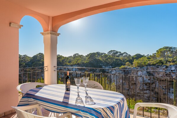 Ein Balkon mit Tisch, zwei Stühlen, einer Flasche und zwei Weingläsern.
