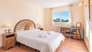 A bedroom with a bed, bedside tables, a desk, a chair, and a window with curtains. - The Torrent's Observer Holiday Home (Cala Pi) Free wifi, Smart Tv, Satellite (Cala Pi - Llucmajor)