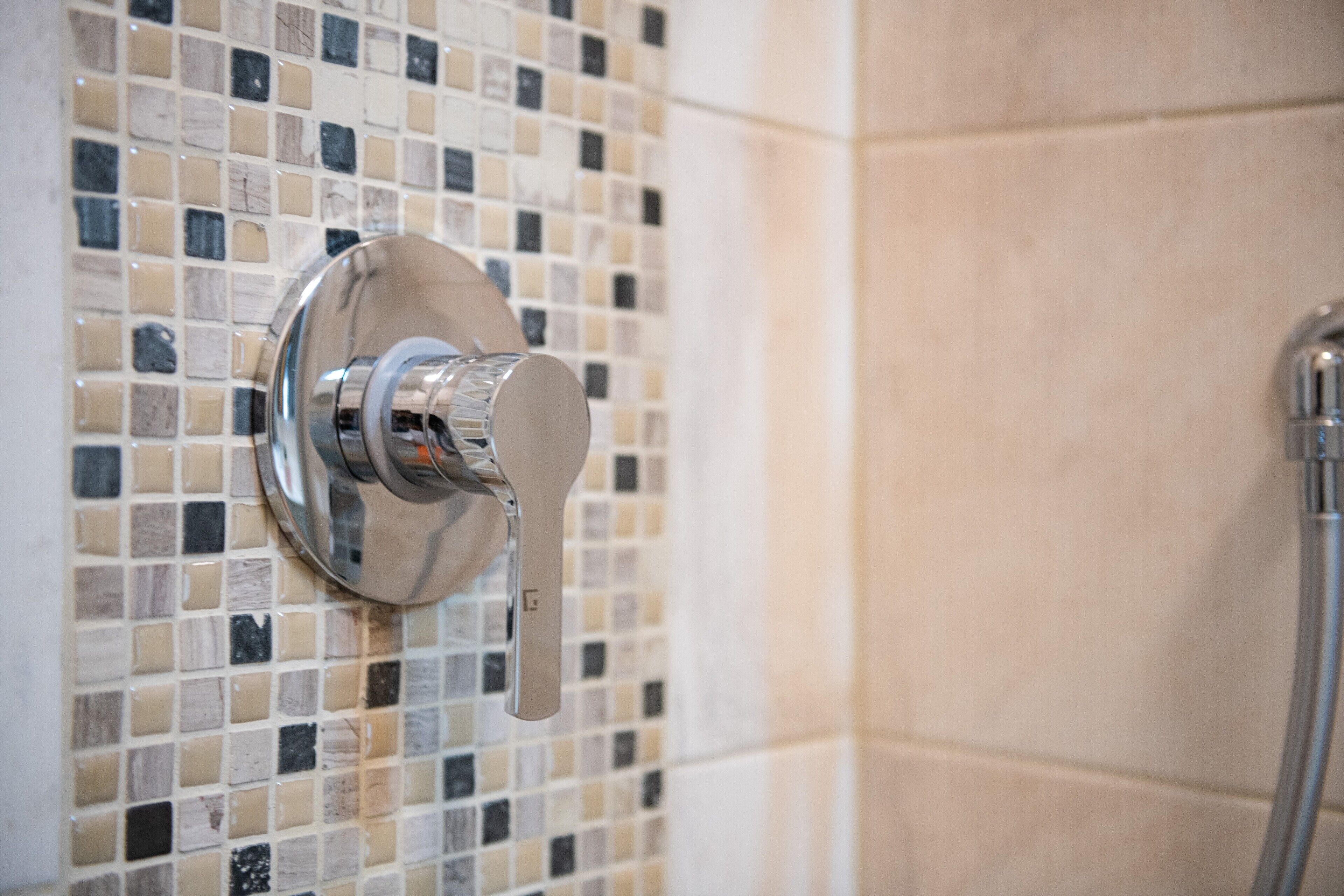 A shower with a chrome faucet and a tiled wall.