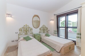Een slaapkamer met twee bedden, een groot raam en een balkon.