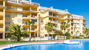 A multi-story hotel with balconies, a swimming pool, and palm trees. - Modern Apartment 'In Jardin Botanico' with Sea View, Pool, Wi-Fi, Garden & Terrace (La Cala de Mijas)