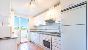 A kitchen with white cabinets, a built-in oven, and a view through the door. - Modern Apartment 'In Jardin Botanico' with Sea View, Pool, Wi-Fi, Garden & Terrace (La Cala de Mijas)