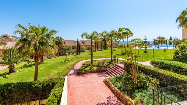 A resort with a pool, palm trees, and a red pathway. - Modern Apartment 'In Jardin Botanico' with Sea View, Pool, Wi-Fi, Garden & Terrace (La Cala de Mijas)