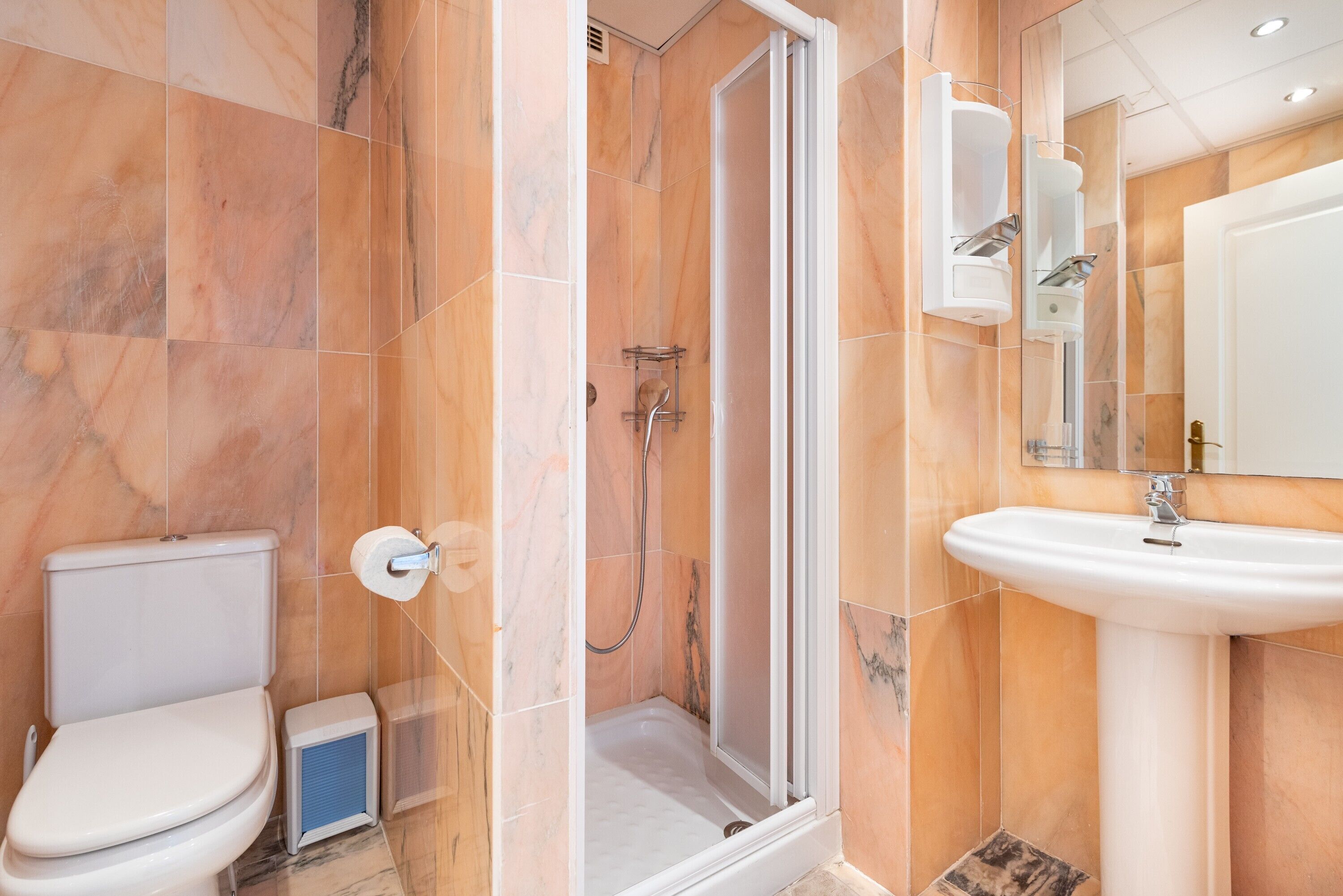 A bathroom with a toilet, shower, and sink.