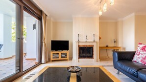 A living room with a TV, fireplace, and a sofa. - Apartment "Finca San Antonio Holiday Rental" with Pool, Terrace & Wi-Fi (Mijas Pueblo)
