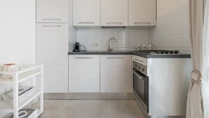 Una cocina moderna con armarios blancos, una estufa a gas y un horno empotrado.