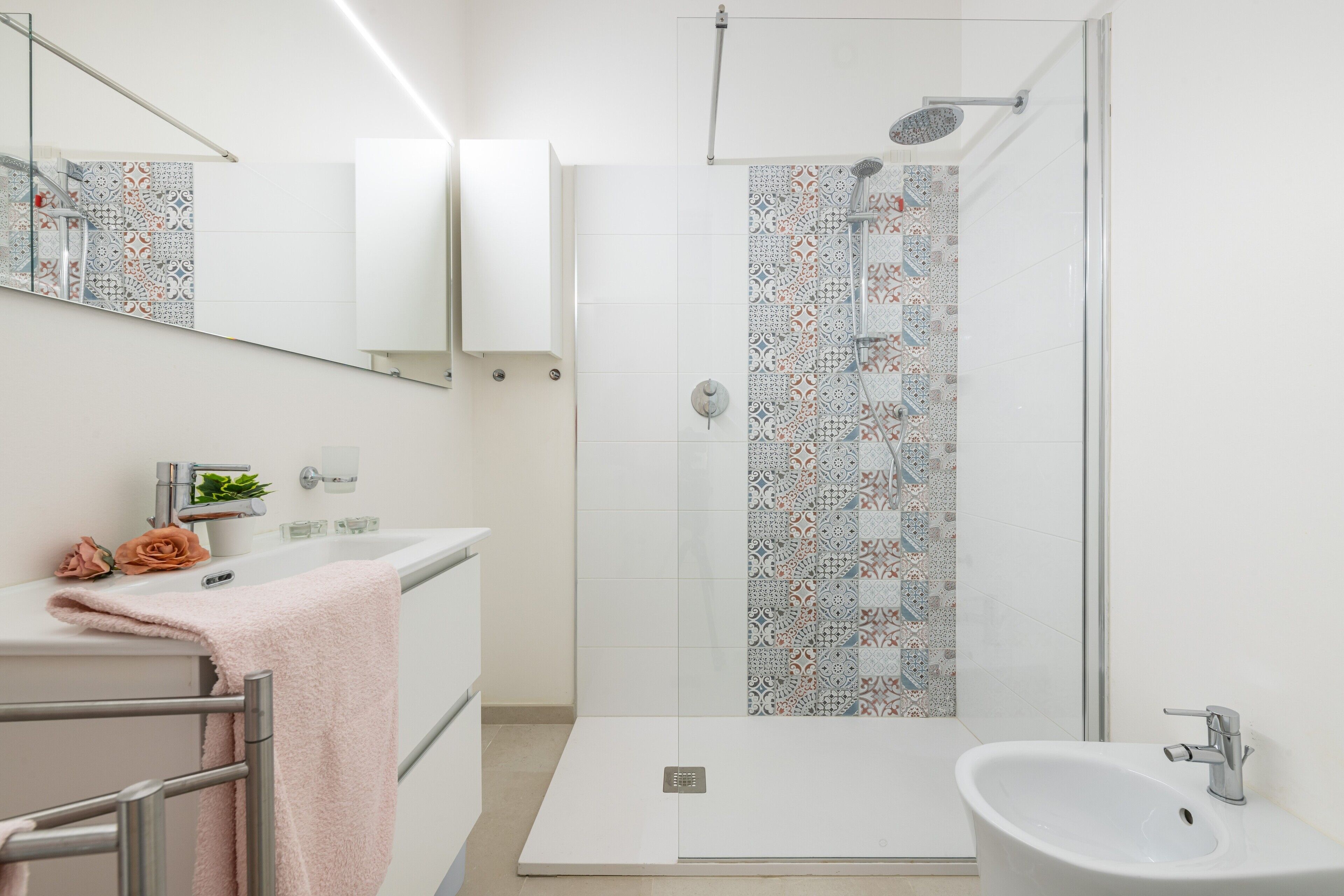 A modern bathroom with a shower, a sink, and a mirror.