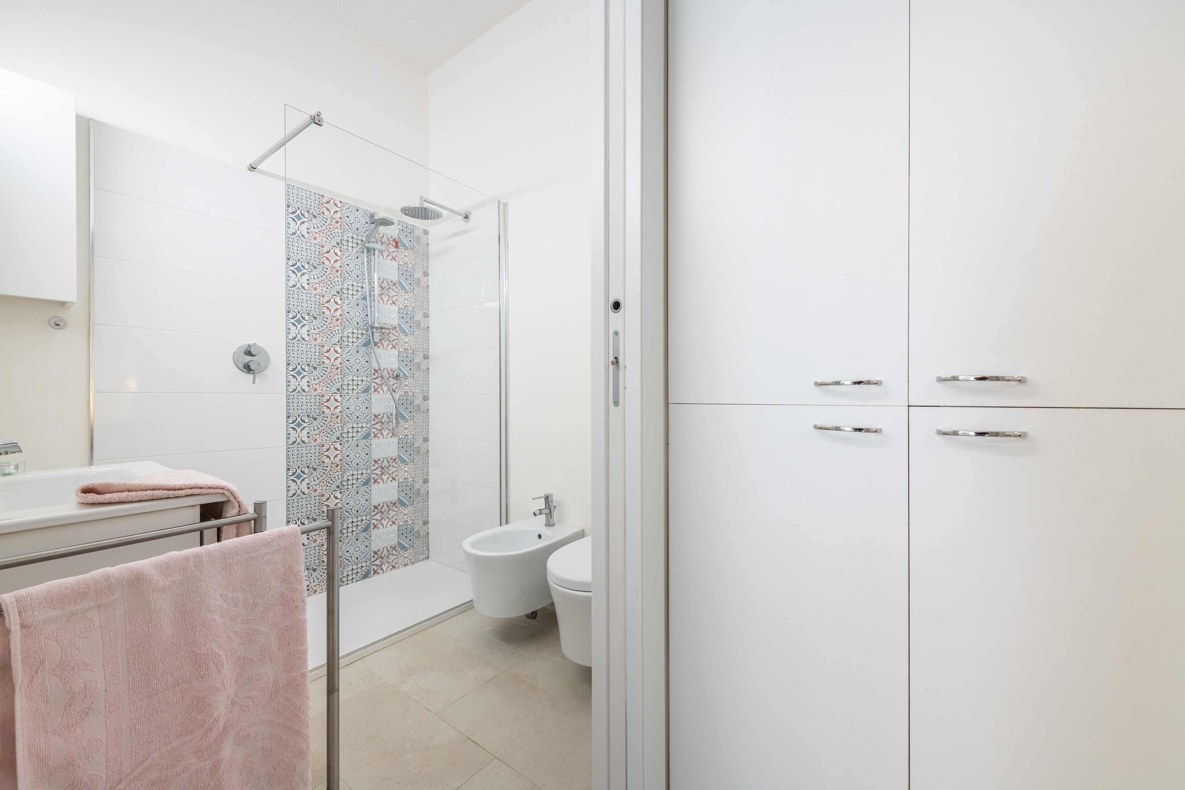 Une salle de bain moderne équipée d’une douche, de toilettes, d’un bidet et d’un porte-serviettes.