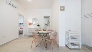 Una cocina moderna con armarios blancos, un espejo redondo y un comedor con una mesa y sillas de vidrio.