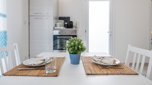 A dining table with two plates, a glass, and a potted plant. - Pet-Friendly Apartment 'La Casa dei Naviganti' with Courtyard and Wi-Fi (Villasimius)