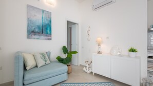A modern living room with a light blue sofa, a large abstract painting, a white cabinet, a potted plant, and a decorative anchor. - Pet-Friendly Apartment 'La Casa dei Naviganti' with Courtyard and Wi-Fi (Villasimius)