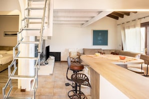 Une cuisine moderne avec un îlot central en bois, une cuisinière intégrée et un escalier menant à un niveau supérieur.