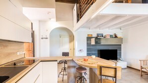 Een moderne keuken met een centraal eiland, barkrukken en een open haard.
