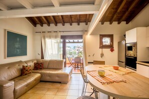 Una sala de estar con sofá, mesa de comedor y zona de cocina con electrodomésticos.
