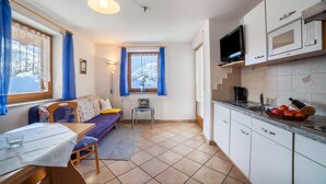 Un espacio habitable compacto con kitchenette, comedor y sofá.