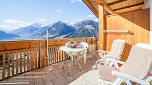 Un balcon en bois, agrémenté d’une table et de chaises, qui offre une vue sur une chaîne de montagnes.