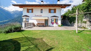 Un bâtiment blanc avec une enseigne indiquant « Roath-Hof », un banc en bois et un mur de pierre surmonté d’une clôture en bois.