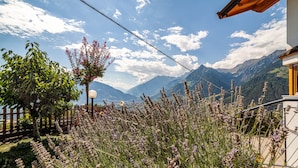 A mountain landscape with a wooden fence, a lamp post, and a building with a sloped roof. - Apartment 'Roath Hof 3' with Mountain View, Shared Garden and Wi-Fi (Schenna)