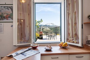 A kitchen with a view of a patio, a dining table, and a fruit bowl on the counter.