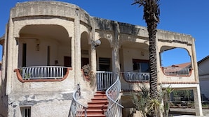 Un edifici amb una escala, balcons i una palmera.