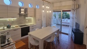 Una cuina moderna amb electrodomèstics integrats, una zona de menjador amb taula i cadires, i un balcó amb vistes.