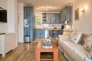 A modern living room with a sofa, coffee table, and a kitchen in the background. - Capuchinos 42 San Juan Capistrano by Casasol (Nerja)