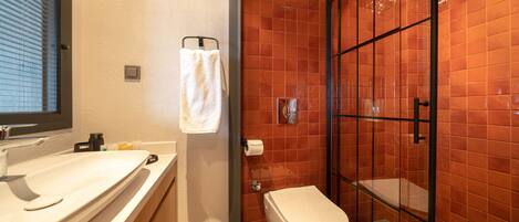 A bathroom with a white sink, toilet, and glass-enclosed shower.
